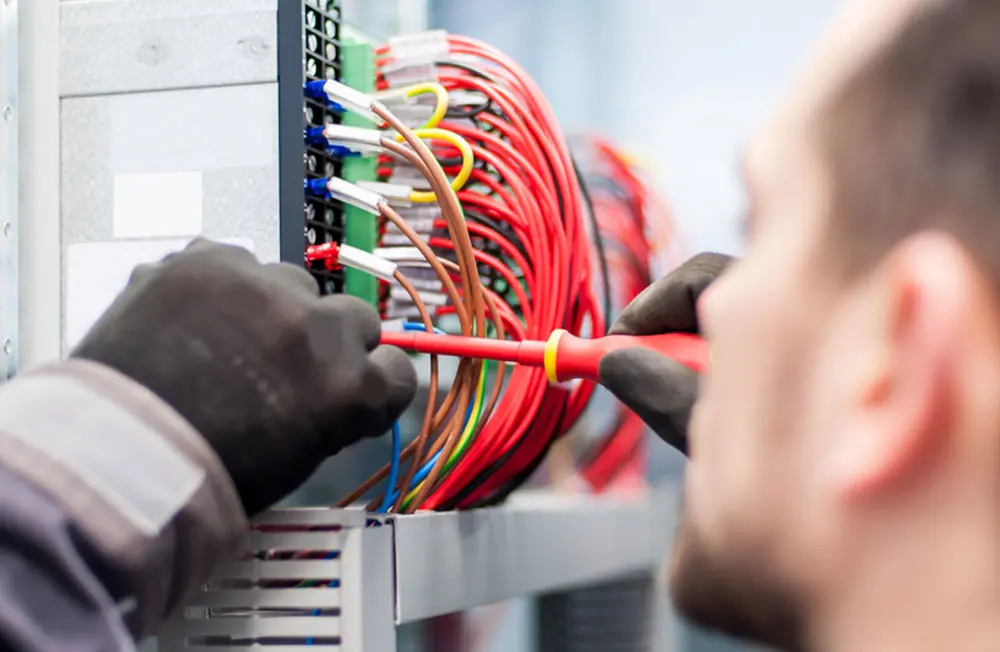 Closeup of electrician engineer works with electric cable wires of fuse switch box. Electrical equipment