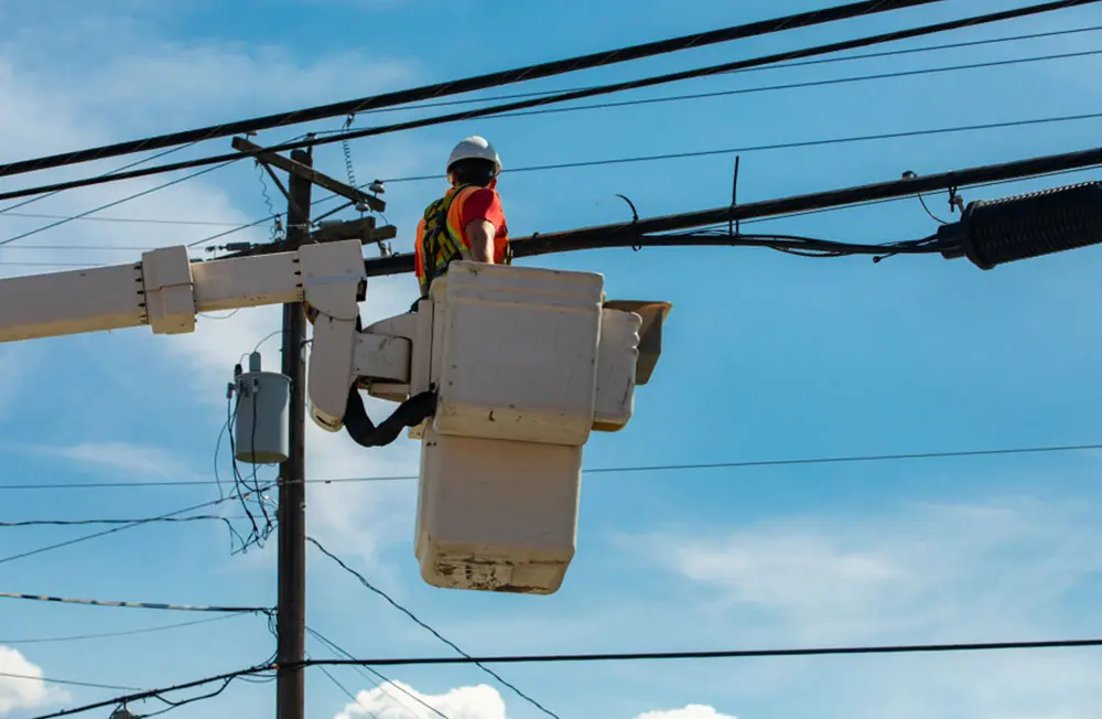 Health and safety in the construction and maintenance industry as a workman is seen from below in a cherry picker by a utility pole